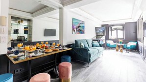A modern living room with a sofa, a dining table set with breakfast, and a TV. - Modern Apartment - 1br/4p - Pereire (Paris)