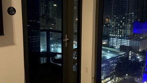 A modern room with a large sliding glass door leading to a city view at night.