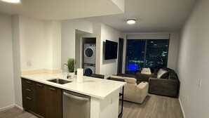 A modern kitchen with a central island, built-in appliances, and a large window offering a city view.