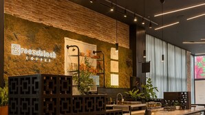 A modern bar area with a brick wall, a neon sign, and a counter with stools.