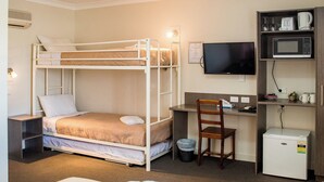 Une chambre d’hôtel équipée d’un lit superposé, d’un bureau et d’une télévision, ainsi que d’un four à micro-ondes et d’un petit réfrigérateur.
