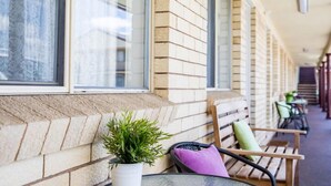 Un espace extérieur abrité, doté de murs en briques, d’une plante en pot et de bancs en bois.