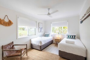 A bedroom with two beds, a ceiling fan, and a view of greenery outside. - Crest on Convent - Oceanstays - Steps to Cafes, Beaches & Town (Yamba)