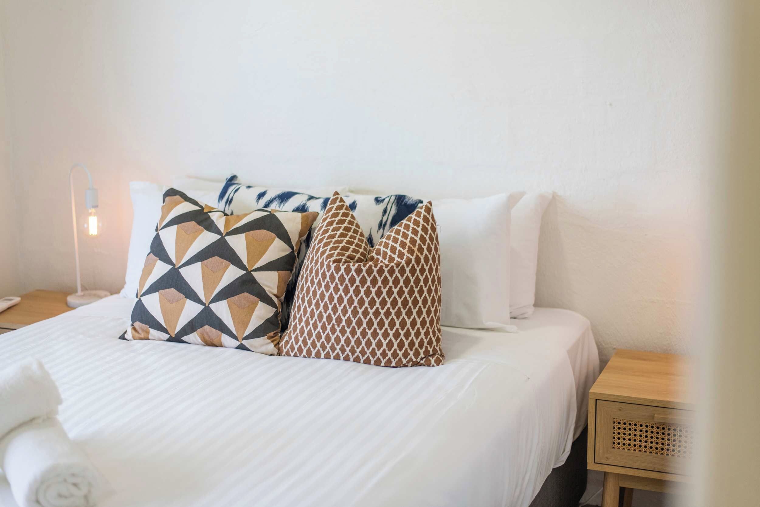 A neatly made bed with patterned pillows and a white comforter.