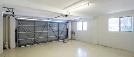 Eine saubere, leere Garage mit einer Metallgaragentür, Neonbeleuchtung und einem Fenster an der rechten Wand.