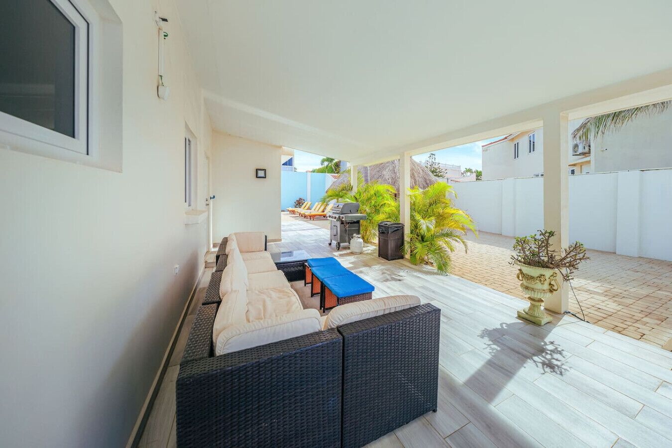 A covered outdoor area with a sofa, a table, and a grill.