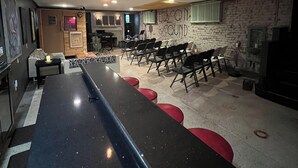A bar area with a long counter, multiple chairs, and hanging pendant lights.