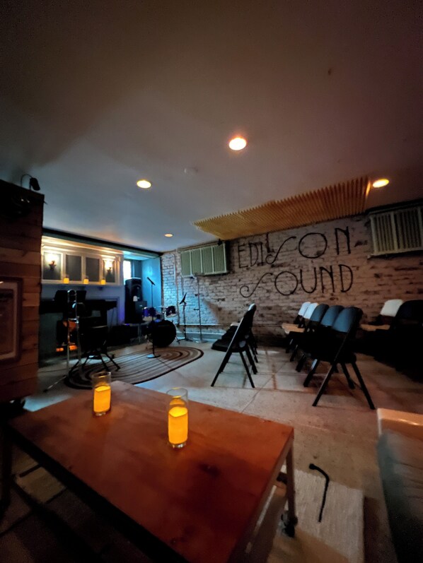 Una habitación acogedora con pared de ladrillo, una mesa de madera con dos velas y un rincón de estar con sillas.
