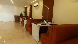 A restaurant with booths and tables, a reception desk, and a tiled floor. - Hotel R Raghavam (Ayodhya)