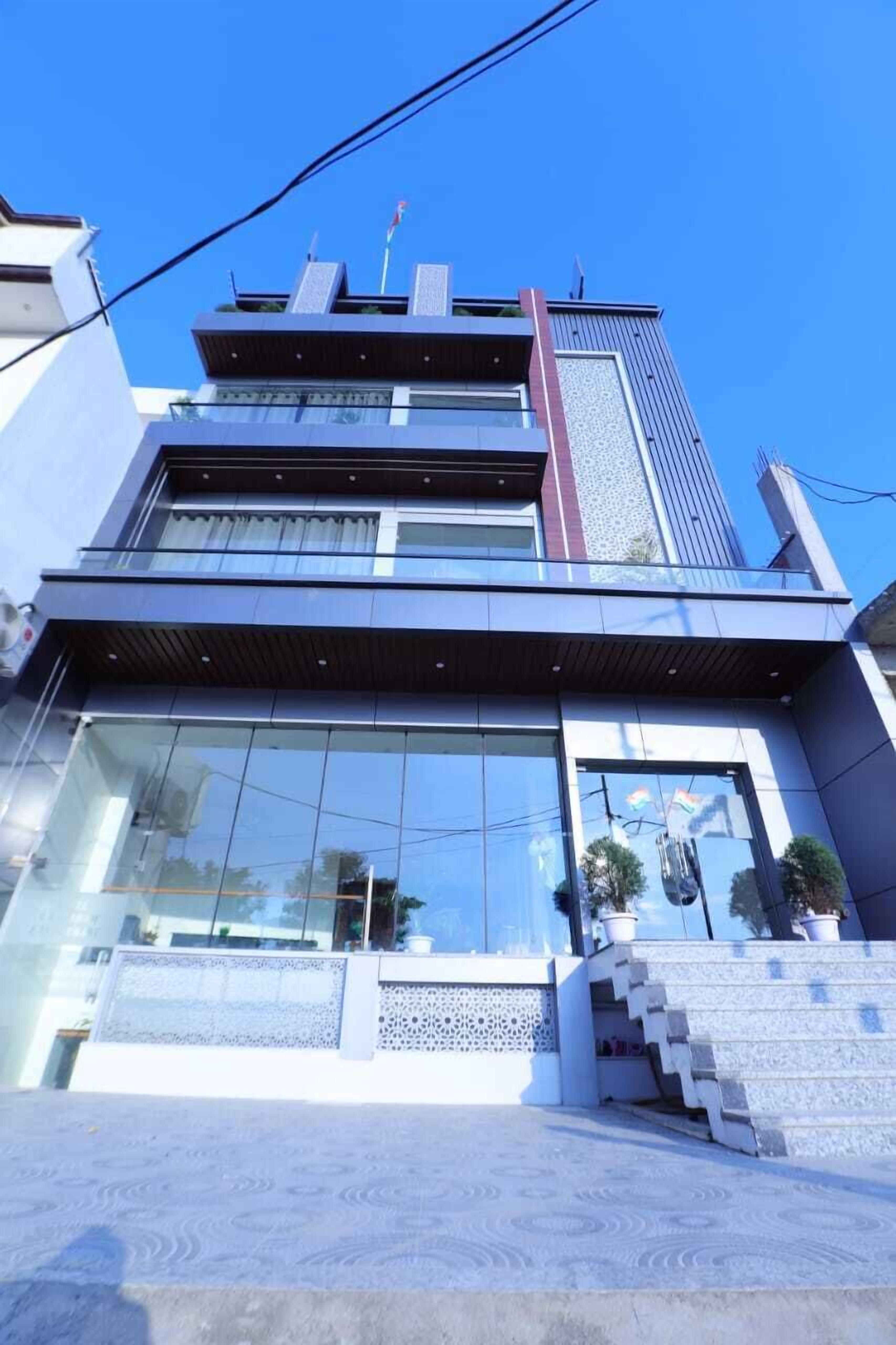 A modern building with a glass facade, multiple floors, and a staircase leading to the entrance.
