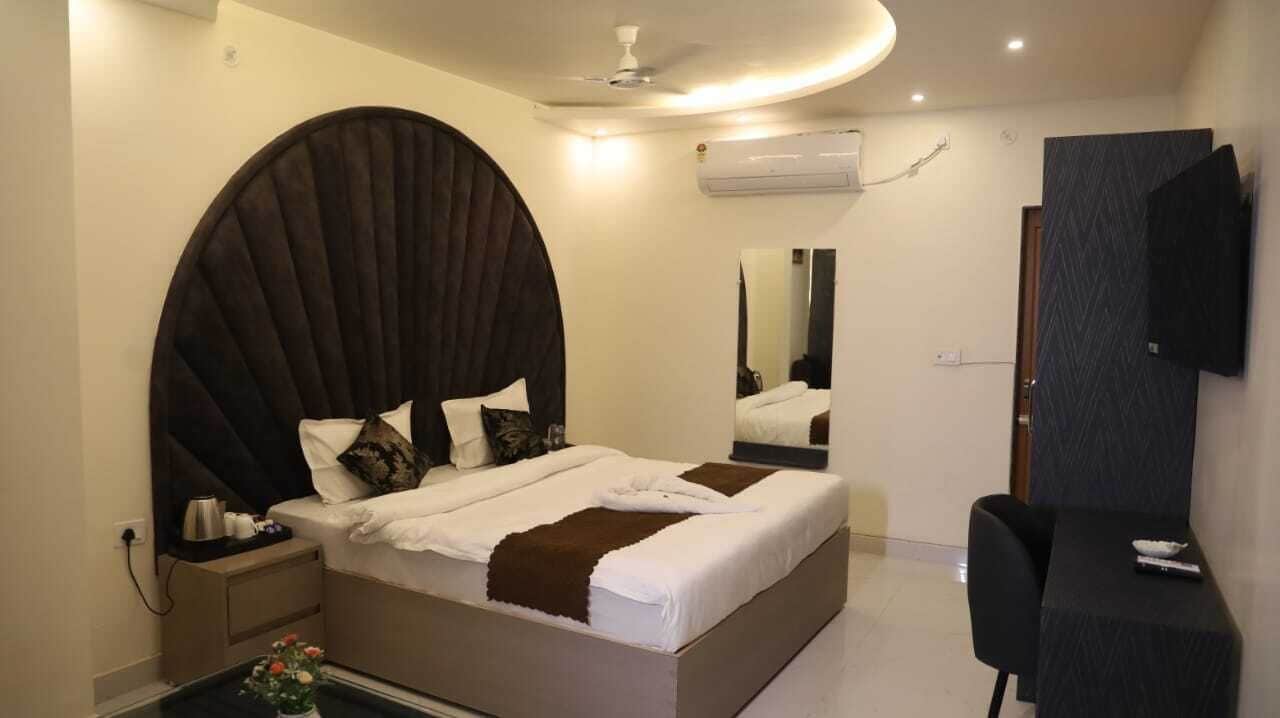 Une chambre à coucher moderne avec un grand lit, une table de chevet, une télévision et une petite table sur laquelle est posé un vase.