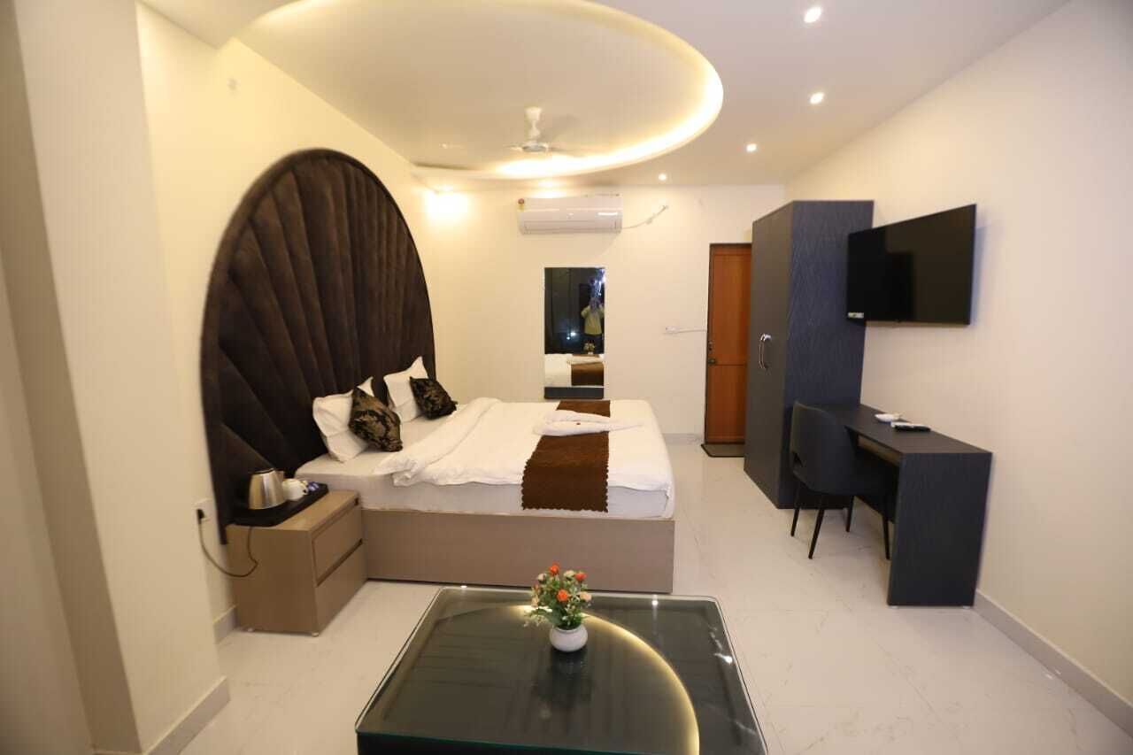 A modern bedroom with a large bed, a desk, and a TV.