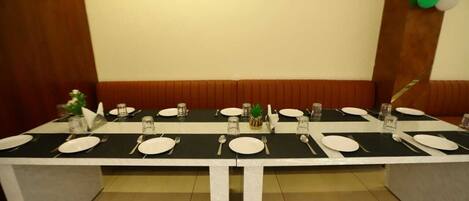 A conference table set for a meeting with white plates, cutlery, and glassware.