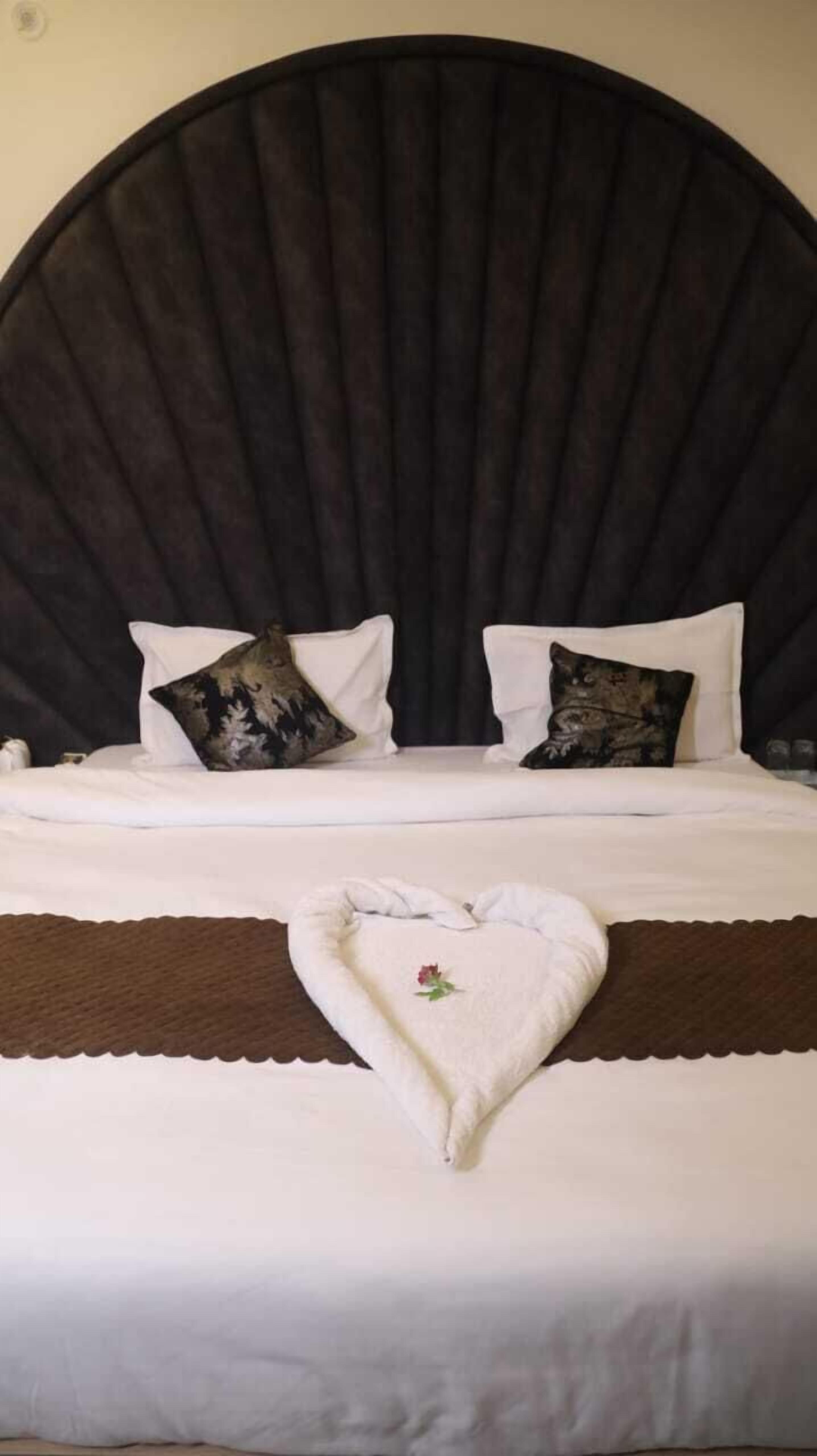 A bed with a dark headboard, white bedding, and decorative pillows.