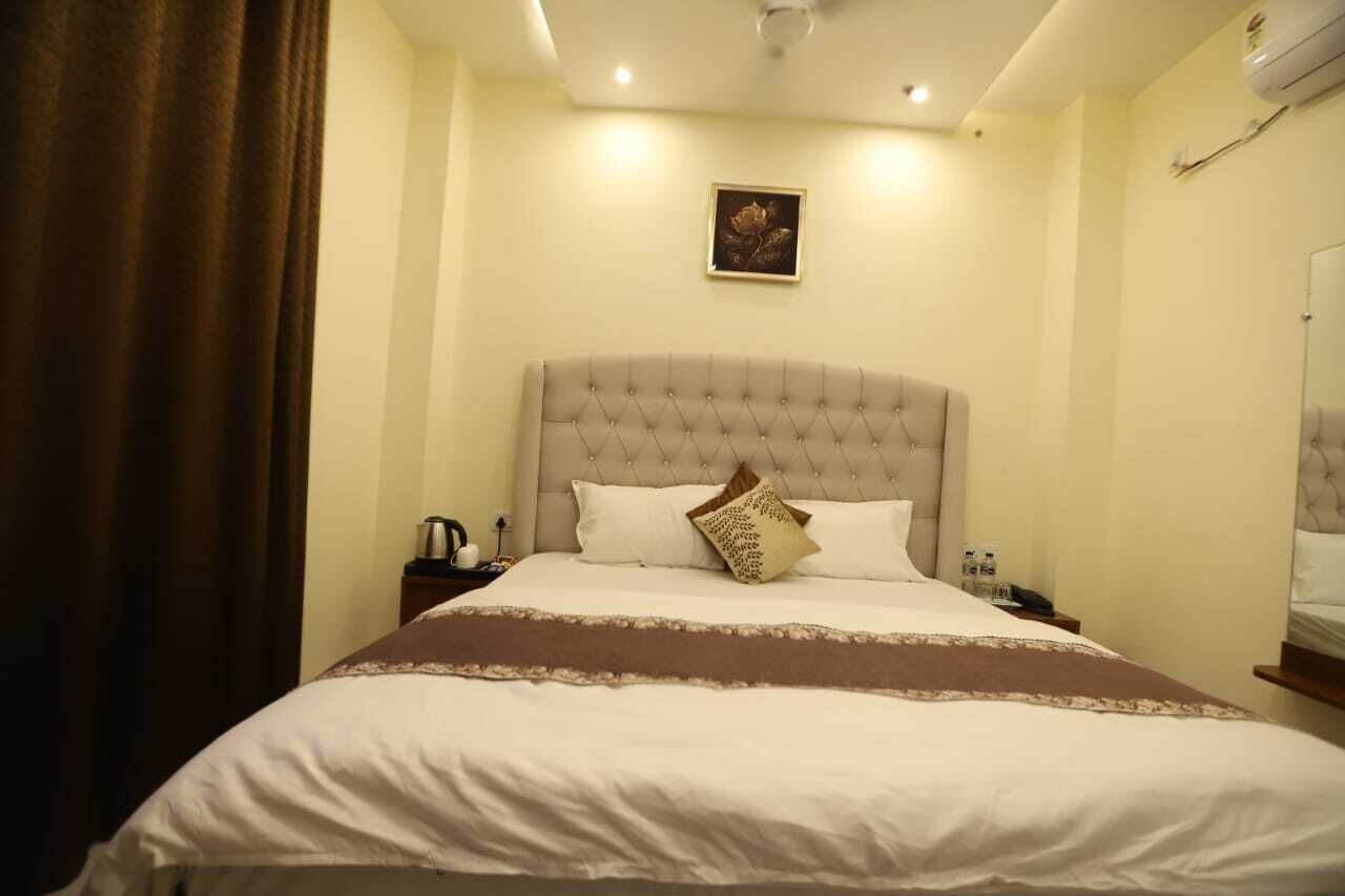 A neatly made bed with a tufted headboard, a brown throw blanket, and a single decorative pillow.