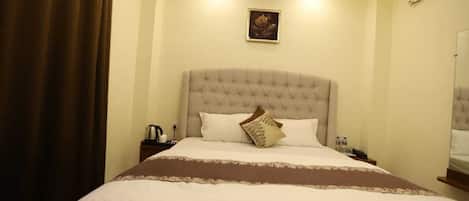 A neatly made bed with a tufted headboard, a brown throw blanket, and a single decorative pillow.