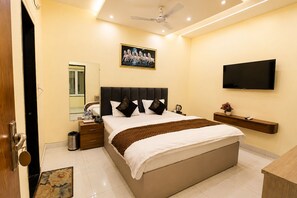 A hotel room with a bed, bedside table, mirror, TV, and a ceiling fan.