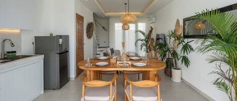 A modern kitchen with a central island, stainless steel appliances, and a dining area with wooden chairs and a round table.