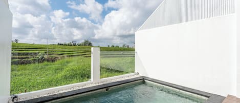 A pool with a view of a green field and a white building.