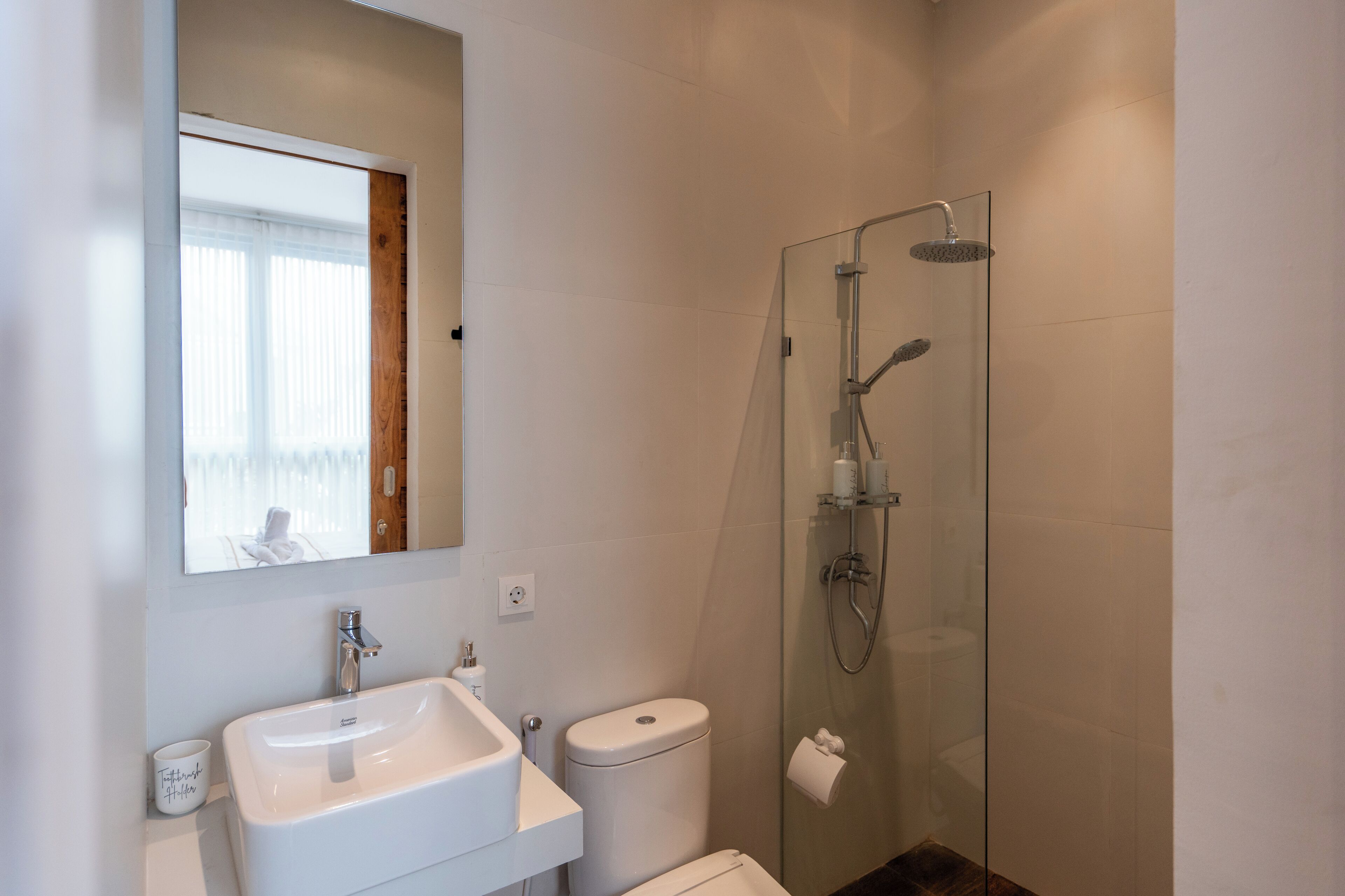 Une salle de bain moderne avec une douche à parois de verre, un lavabo blanc et des toilettes.