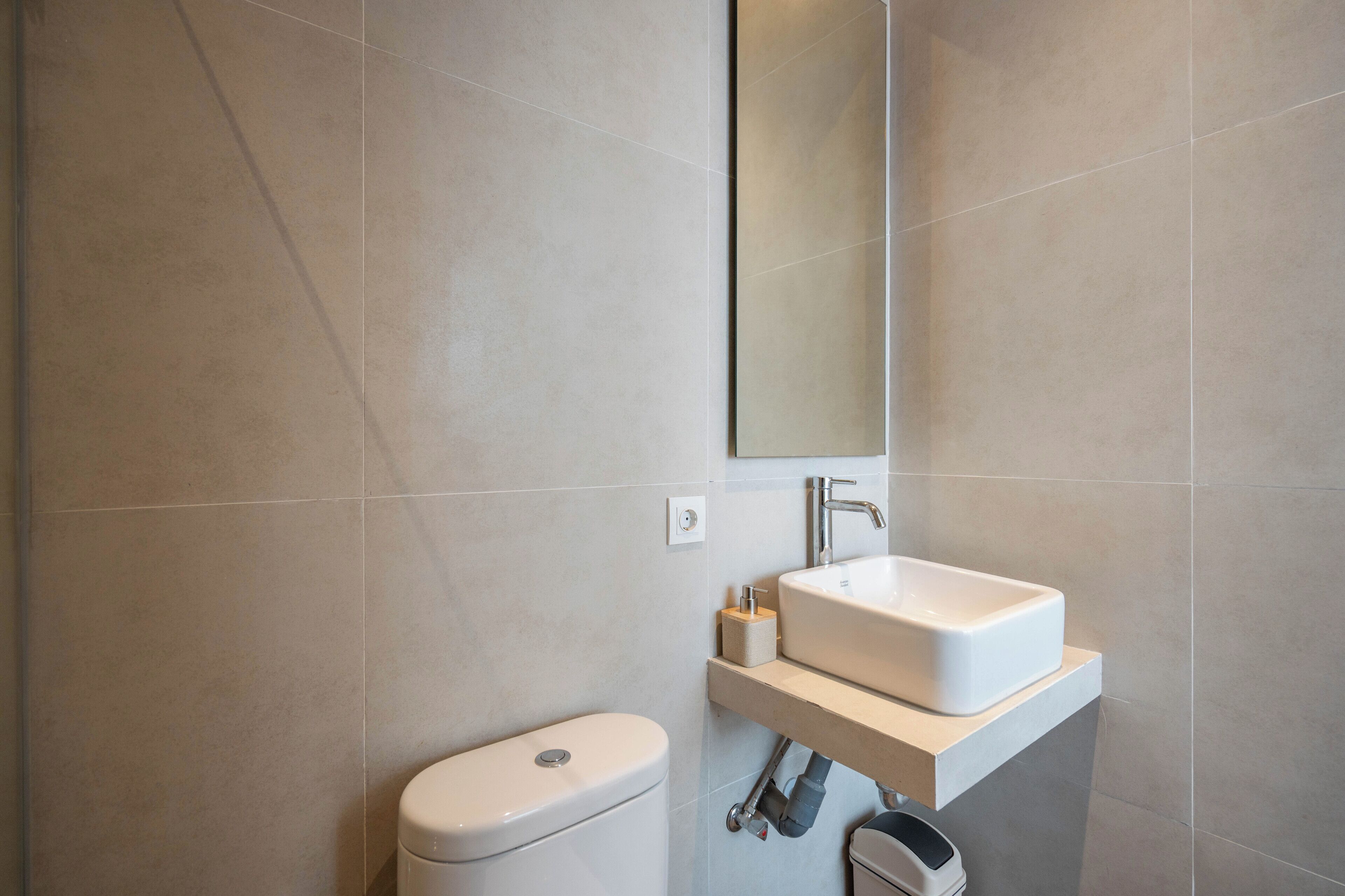 A modern bathroom with a toilet, a sink, and a mirror.