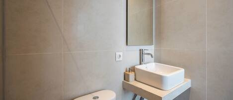 A modern bathroom with a toilet, a sink, and a mirror.