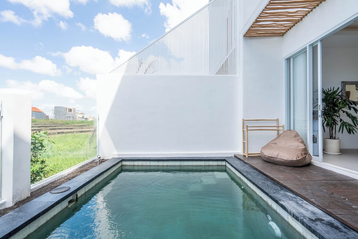 A modern outdoor pool area with a clear view of the surrounding landscape, a wooden deck, and a potted plant.