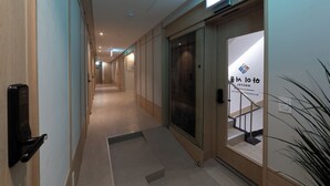 Een hotelhal met een receptiebalie, een glazen deur en een trap naar de verdieping erboven.
