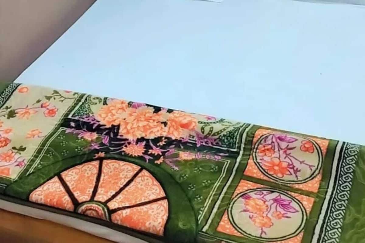 Een bed met een bloemendecor en twee witte kussens.