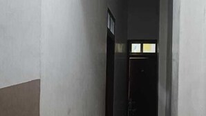 A narrow hallway with a door at the end, a tiled floor, and a light fixture on the ceiling. - Satvika Guest House (Danta Ramgarh)