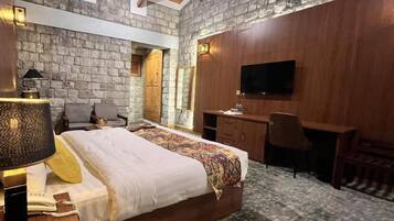 A bedroom with a bed, desk, chair, and TV.