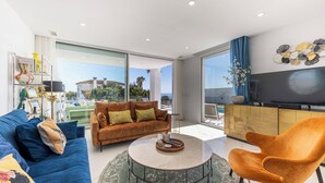 A modern living room with a sofa, armchair, and coffee table, a TV, and a view of the sea. - Heated Pool Villa / Sea & Gibraltar View (Torreguadiaro)
