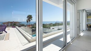 A modern balcony with a clear view of the sea and a building in the background. - Heated Pool Villa / Sea & Gibraltar View (Torreguadiaro)