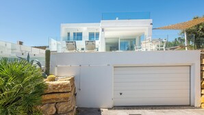 A modern two-story house with a white exterior, a garage, and a clear view of the surrounding area. - Heated Pool Villa / Sea & Gibraltar View (Torreguadiaro)