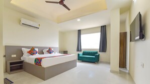A modern hotel room with a bed, a sofa, a ceiling fan, an air conditioning unit, and a TV mounted on the wall. - Fabhotel Cozzy Stay (Jaipur)