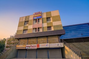 A multi-story building with a sign for 'Atithi Lodge AC Rooms' and various other businesses including 'Skubham Batteries' and 'Sun Cargo Services'. - FabHotel Wagholi Inn (Pune)