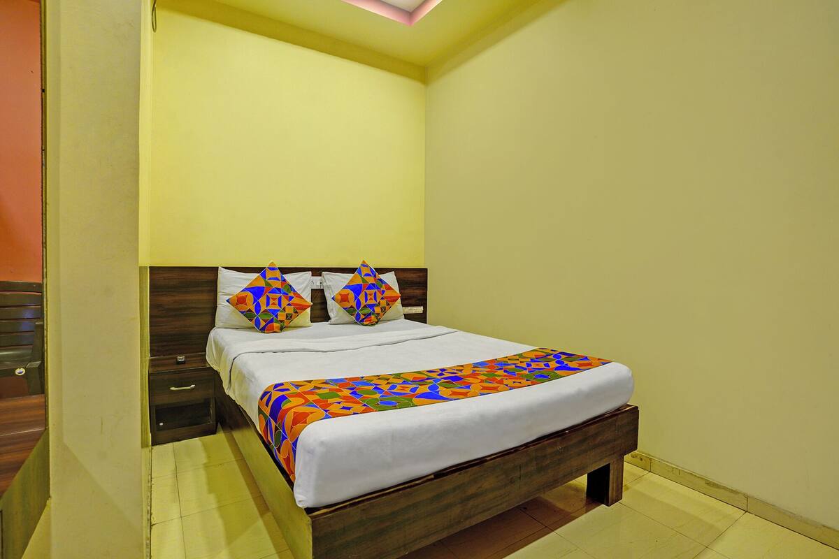 A single bed with a wooden headboard and a colorful geometric-patterned bedspread.