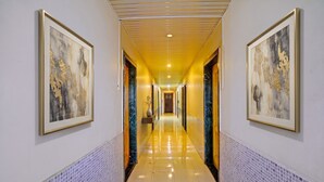 A hallway with framed abstract art, a tiled floor, and a central door leading to another room. - FabHotel Wagholi Inn (Pune)