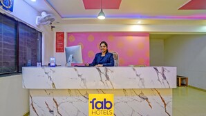 A hotel reception desk with a marble design, a computer, and a logo for 'fab hotels'. - FabHotel Wagholi Inn (Pune)
