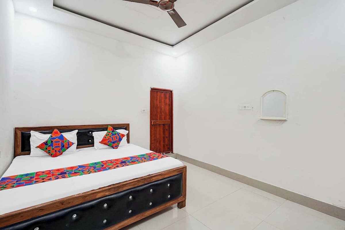 Un dormitorio con cama, ventilador de techo, armario de madera y una ventana pequeña.