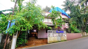A two-story building with a gated entrance, surrounded by lush greenery and palm trees. - Fabhotel Peaceful Studio Aai Bungalow (Panvel)