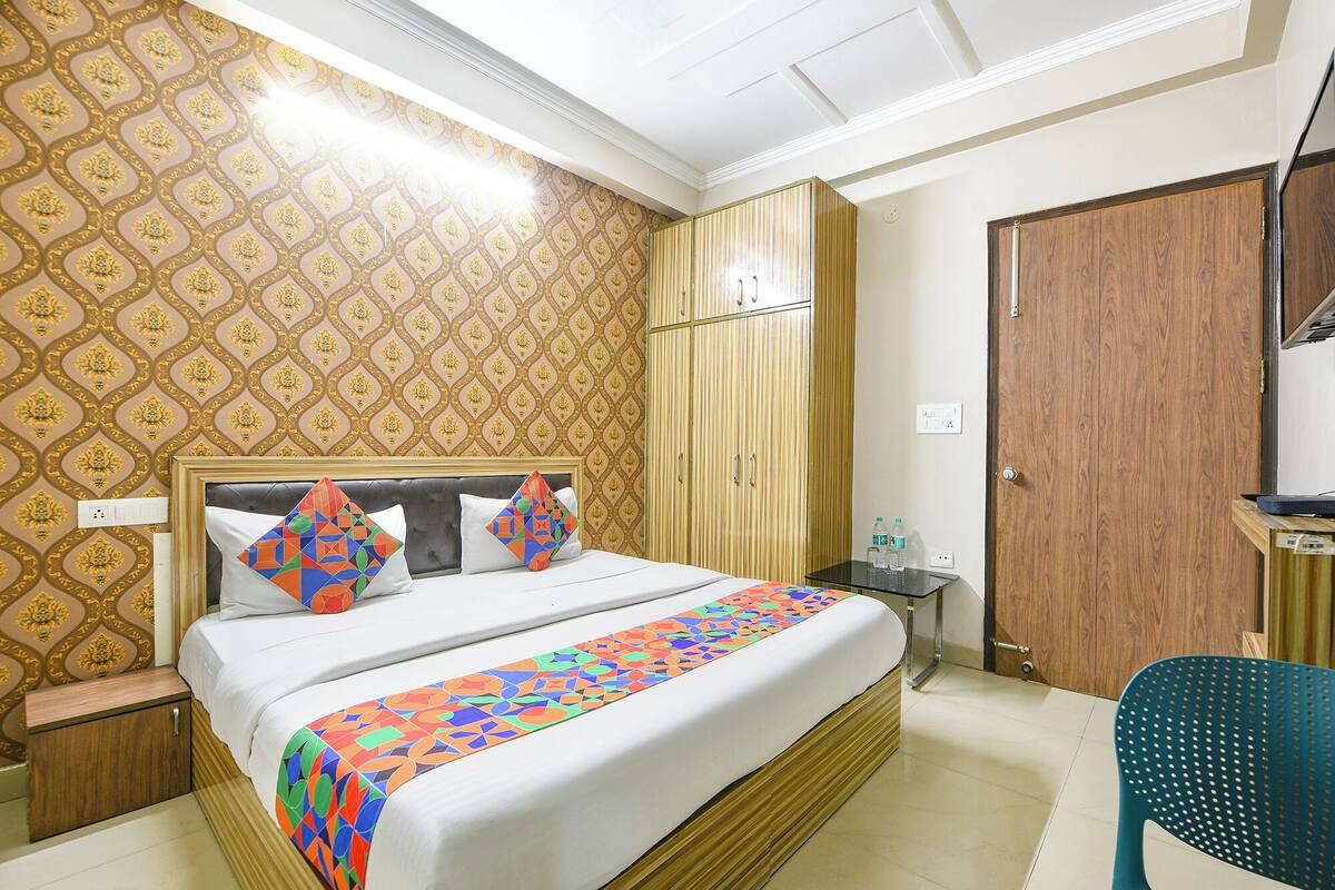A hotel room with a bed, a wardrobe, a nightstand, and a chair.