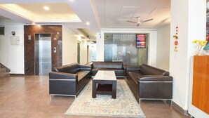 A lobby with a reception desk, seating area, and an elevator. - Fabhotel The Flora (Gurugram)