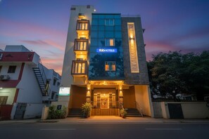 Un hotel moderno con un cartello ben visibile 'fabHOTELS', un ingresso 'SB Mansion' e una facciata illuminata.