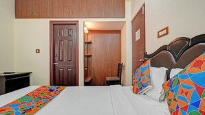 A bedroom with a bed, a chair, a desk, and a wardrobe. - Fabhotel Delight Suite Service Apartments (Bangalore)