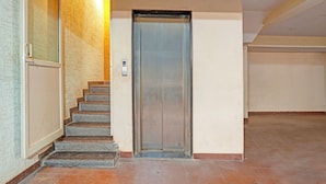 A narrow stairway leading to a door with a metallic elevator. - Fabhotel Delight Suite Service Apartments (Bangalore)