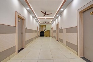 Um corredor comprido e estreito com ventilador de teto, iluminação embutida e uma escada no final.