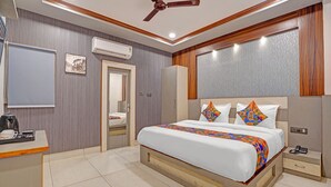 A modern hotel room with a large bed, a desk, a wardrobe, and a ceiling fan. - Fabhotel Kr Inn (Mathura)