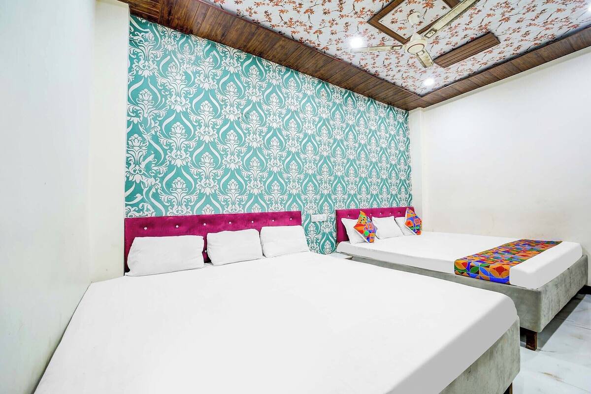 A hotel room with two beds, a patterned wall, and a ceiling fan.