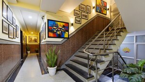 A modern hotel lobby with a staircase, framed artwork, and potted plants. - Fabhotel Tip Top (Jaipur)